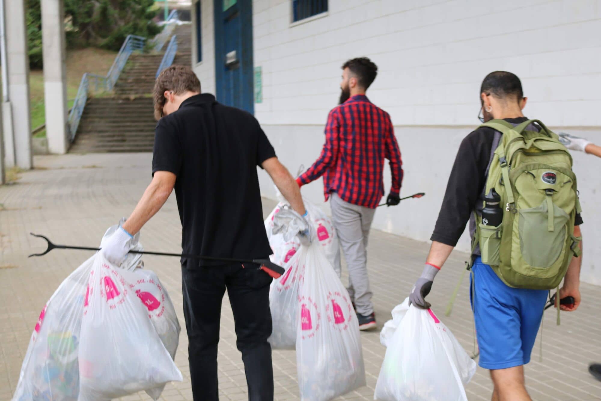 Tres voluntarios caminan con bolsas llenas