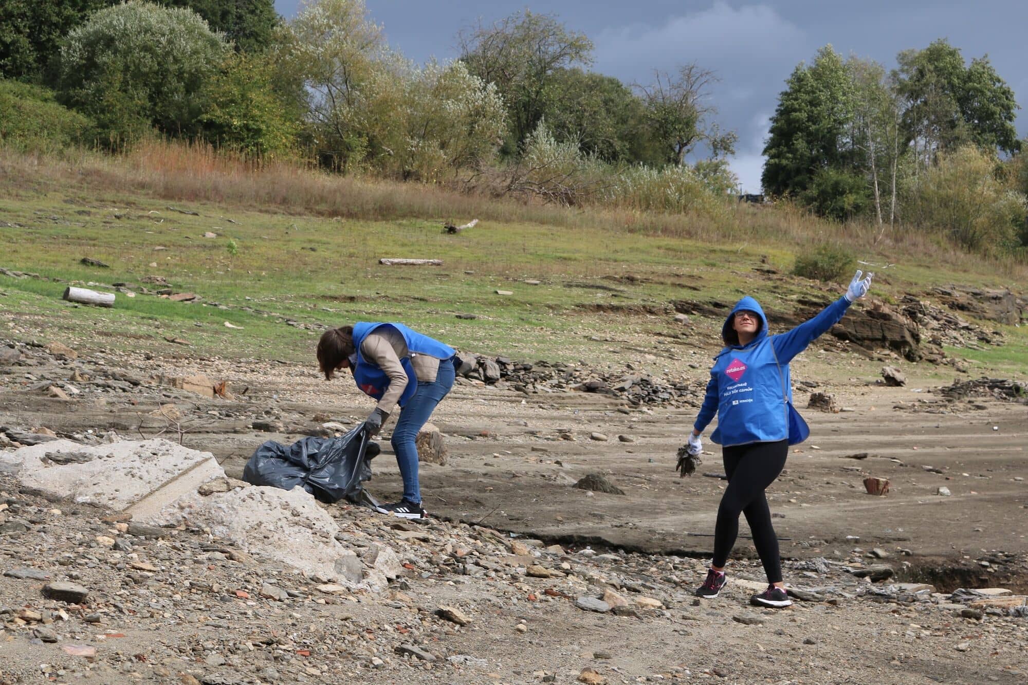 Voluntaria levanta el brazo celebrando en la ribera de un embalse