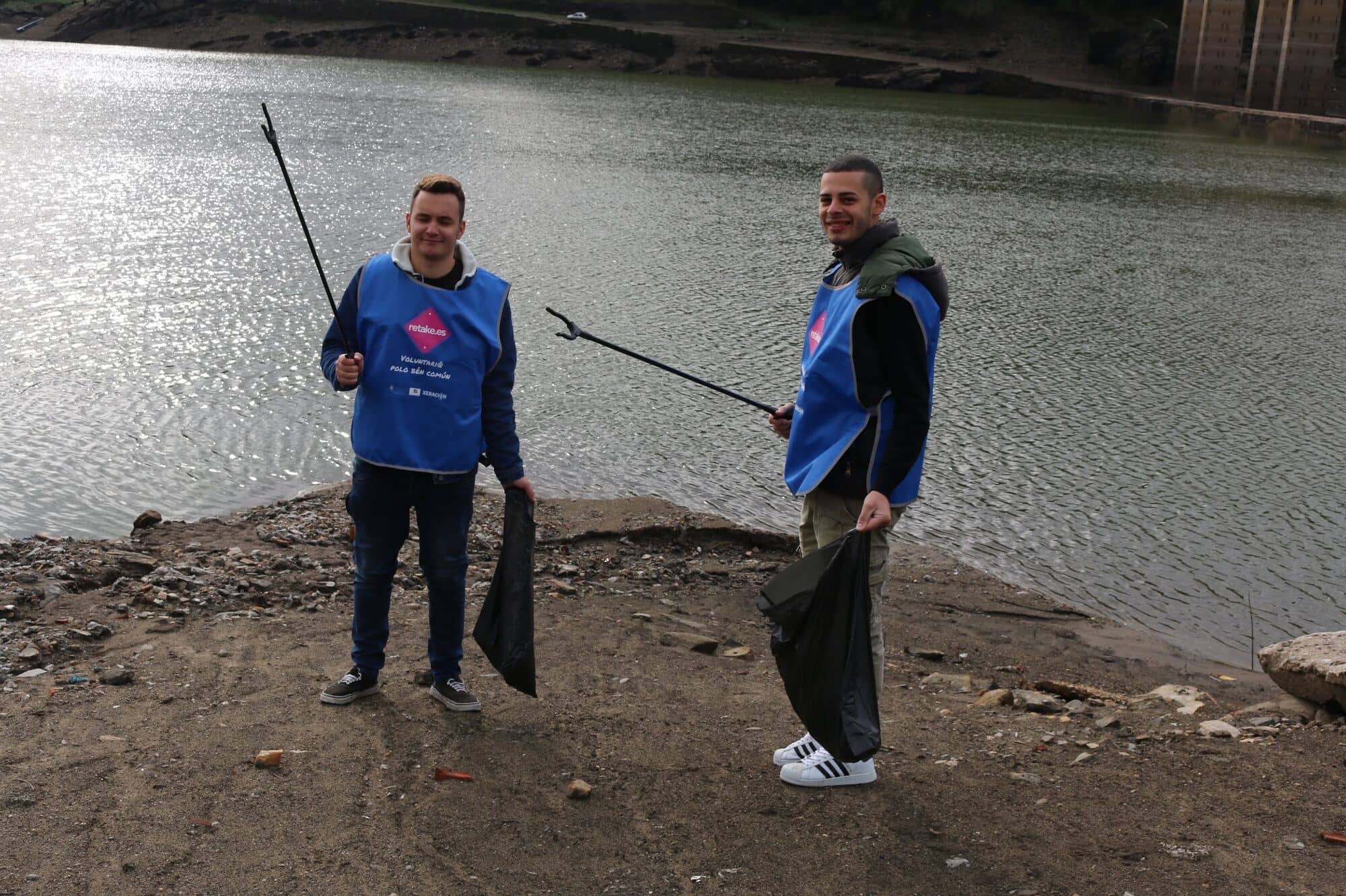 Dos voluntarios con pinzas junto al agua